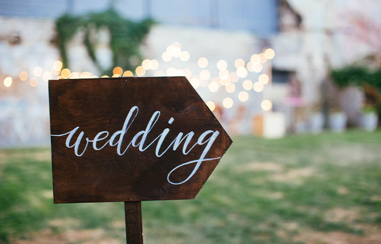 Sign that says wedding on it in front of a pretty wedding venue