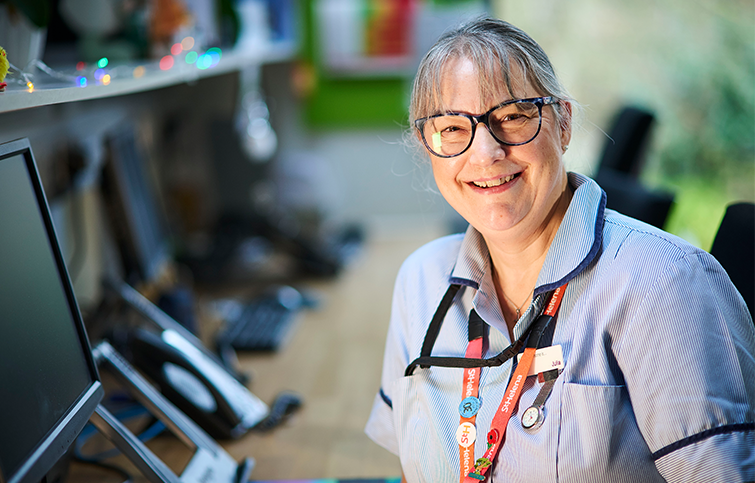 A smiling nurse sitting at a computer