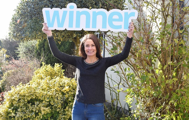 A woman holding a winner sign