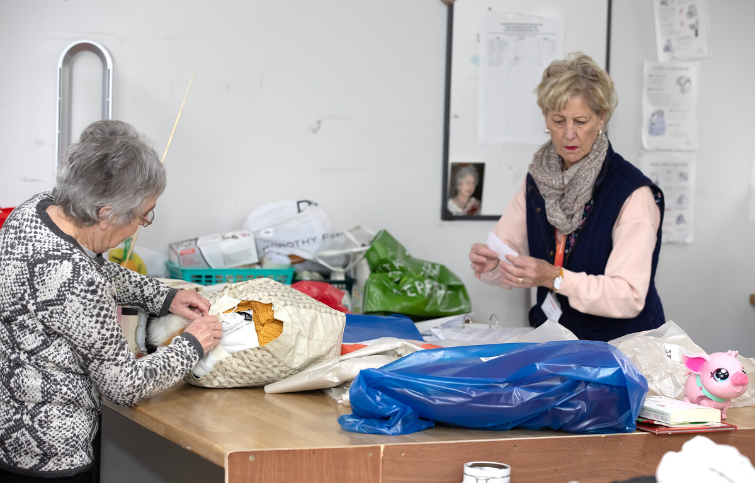 2 female volunteers help sort donations